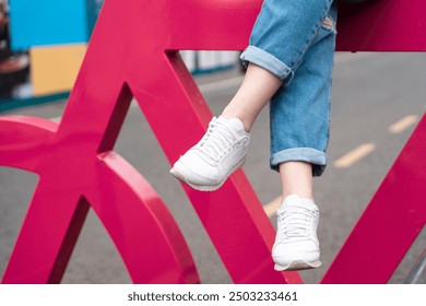 Person Relaxing With Feet Dangling Over Bright Pink Structure in Urban Setting on Sunny Day - Powered by Shutterstock