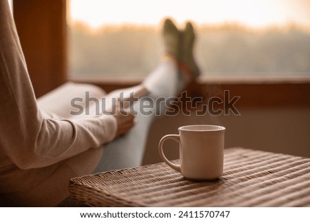 Person relaxing at home reading book feeling relaxed cozy enjoying cup of tea coffee 