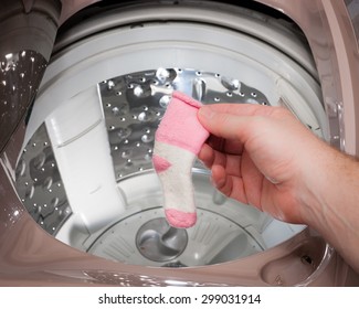 A Person Retrieves A Single Sock From The Washing Machine.