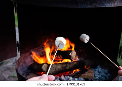 Person Roasting Over Fire Flames A Marshmallows Over Campfire At Night On A Summer Day, For Smores Or Snack Closeup