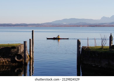 Person rowing in a boat on the Chiemsee lake in Chiemgau Bavaria Bayern Germany Deutschland. Beautiful lake in front of the mountains of the Bavarian alps