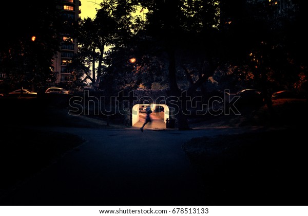 Person running past Dark City Bridge Underpass\
Sidewalk at Night