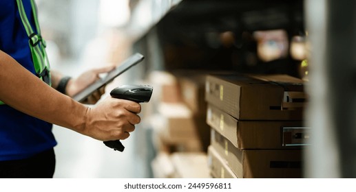 A person is scanning a barcode with a tablet. The person is wearing a green vest. Concept of efficiency and organization in a warehouse or store setting - Powered by Shutterstock