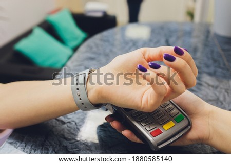 Person scanning smart watch for payment close-up.