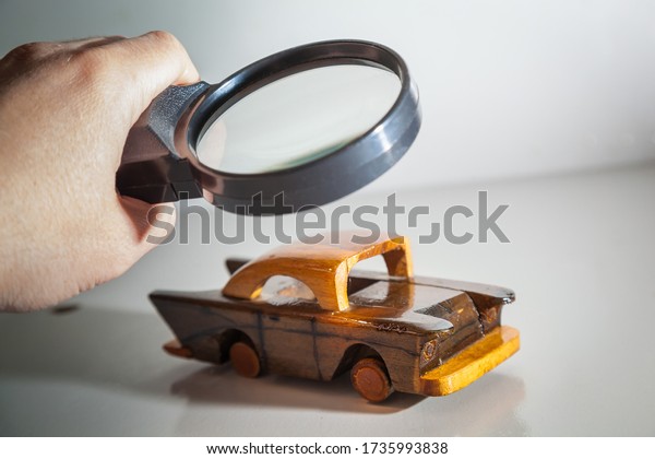 Person Scrutinizing A Wooden
Car Model Using Magnifying Glass. Car search. Vehicle inspection
with a magnifying glass. A man looks at a toy car with a magnifying
glass.