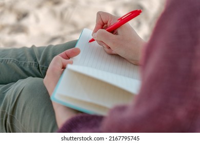 Person Seated On The Beach Taking Notes In The Diary