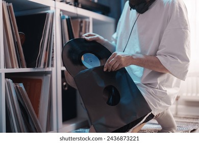 A person selects a vinyl record from a collection, showcasing music appreciation. - Powered by Shutterstock