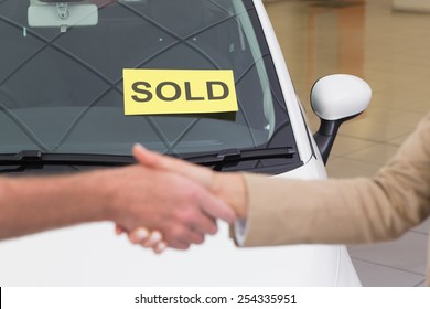 Person Shaking Hands In Front Of A Sold Car At New Car Showroom