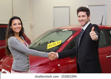 Person Shaking Hands In Front Of A Sold Car At New Car Showroom