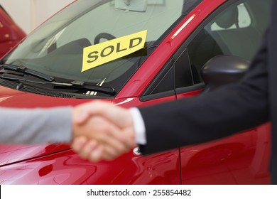 Person Shaking Hands In Front Of A Sold Car At New Car Showroom