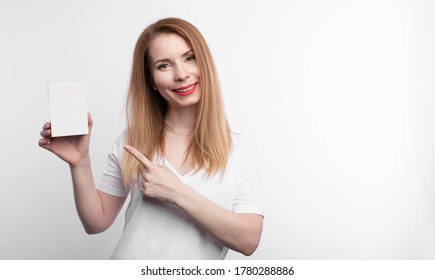 Person Showing Business Card. Casual Woman Smiling Holding The Card. Shallow Depth Of Field, Focus On Paper With Empty Copy Space.