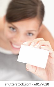 Person Showing Business Card. Casual Woman Smiling Holding The Card. Shallow Depth Of Field, Focus On Paper With Empty Copy Space.