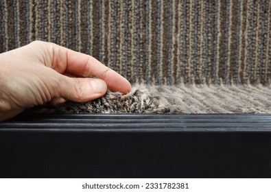 Person showing frayed carpet coming loose on stairstep, stair nosing or stair edging. High traffic staircase with commercial carpet damage by the edge, causing tripping hazard. Selective focus.