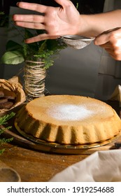 Person Sifting Powdered Sugar Into Cake