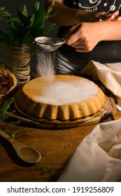 Person Sifting Powdered Sugar Into Cake