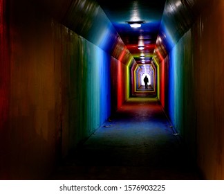 Person silhouetted silhouette walking through colorful tunnel towards achievement