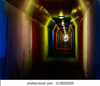 Person silhouetted silhouette walking through colorful tunnel towards achievement