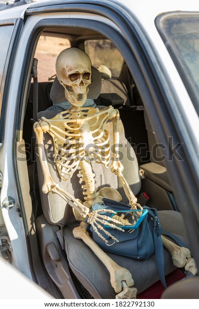 Person sitting in car playing on cell phone
becomes skeleton after waiting so
long