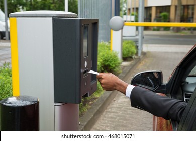 Person Sitting In Car Using Parking Machine To Pay For Parking