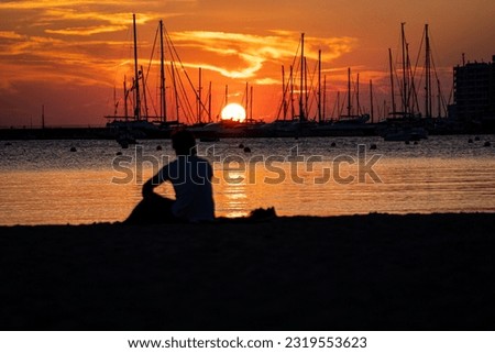 Person sitting on the beach watching sunset in harbour