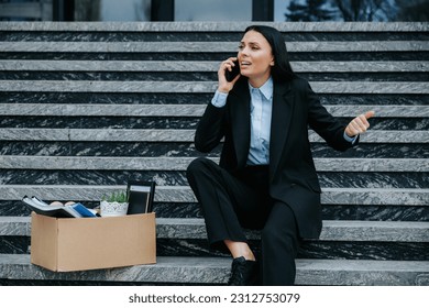 A person sitting on the steps, talking on the mobile phone, and feeling unhappy due to their job loss. Confused and Distressed Woman on Phone Discussing Loss of Work - Powered by Shutterstock