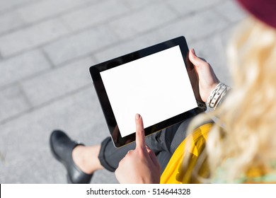 Person sitting outside and using blank screen tablet