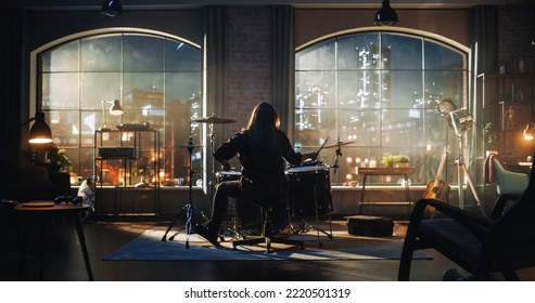 Person Sitting With Their Back To Camera, Playing Drums During Rehearsal In A Loft Studio With Sunlight. Drummer Practising Alone Before A Live Concert On Stage. Evening Or Night Session.