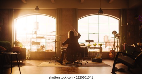 Person Sitting With Their Back To Camera, Playing Drums During A Band Rehearsal In A Loft Studio With Sunlight. Drummer Practising Alone Before A Concert On Stage. Warm Color Editing.