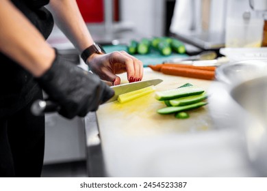 Person skillfully slicing cucumber on a cutting board in a kitchen, with carrots and other ingredients nearby, illustrating meal preparation - Powered by Shutterstock