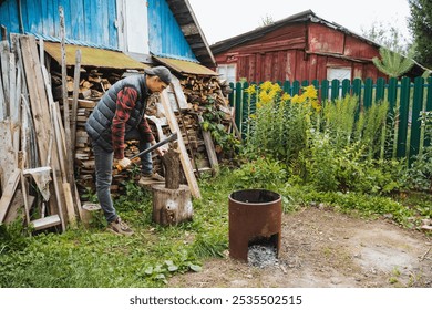 A person is skillfully splitting wood outdoors in a rustic yard, surrounded by lush greenery and a colorful wooden fence, showcasing their commitment to outdoor hobbies - Powered by Shutterstock