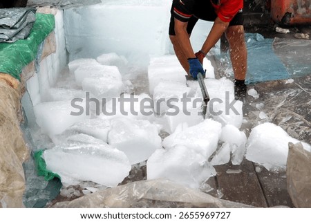 A person skillfully using a sharp axe to chop and break apart large frozen blocks of ice outdoors.