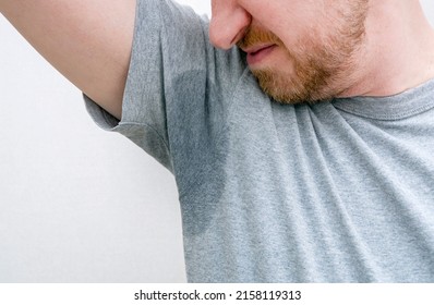 Person Sniffing Armpit. Sweaty Armpit, Wet Underarm, Stain Of Sweat On Grey T-shirt