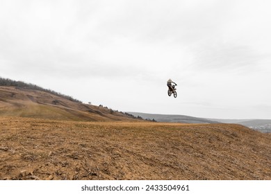 Person soaring on dirt bike in the sky over grassy field - Powered by Shutterstock