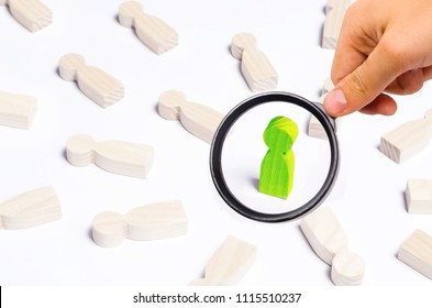 A Person Is In The Spotlight. A Wooden Figure Of A Man. Concept Business Idea. Best In The Business. People Lie Around. Victory, Progress, Innovation. White Background.