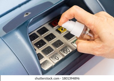 Person Spraying Sanitizer Disinfectant Onto ATM Key Pad To Kill Harmful Germs