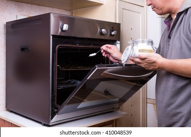 Person Sprinkling Baking Soda Into An Oily Oven As Cleansing Agent To Clean