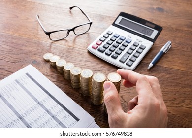 Person Stacking Coins With Calculator And Eyeglasses On Wooden Desk. Income Tax Rise Concept - Shutterstock ID 576749818
