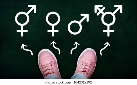 A Person Standing On Chalkboard With Gender Symbols Of Male, Female, Bigender And Transgender.  Concept Of Choice Or Gender Confusion Or Dysphoria.