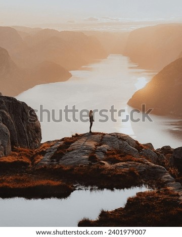 Similar – Man sitting on a cliff of a fjord with low sun on the European Arctic Ocean