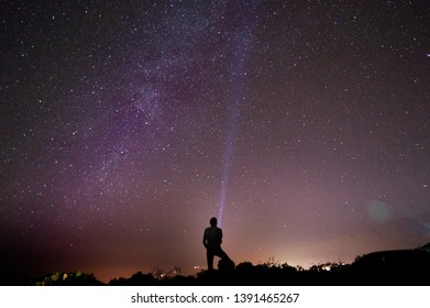 Person standing on rock looking at stars