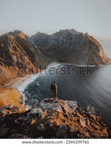 Similar – Man sitting on a cliff of a fjord with low sun on the European Arctic Ocean