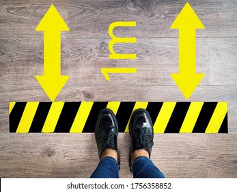 Person Stands In Line With Yellow And Black Stripes Keeping Safe Social 1m Distance, Arrow Due To Pandemic. Legs Of Girl In Jeans Waiting In Line At Checkout Counter In Supermarket Top View
