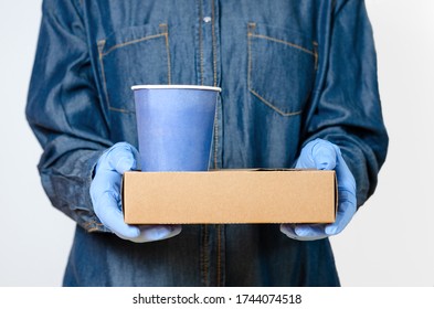 Person With Surgical Gloves Who Brings Coffee To The Door Or Office . Concept Regarding Hygiene And Protection Against The Spread Of Diseases In Food Distribution.