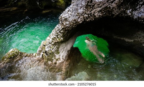 Person Swimming Through Little Elephant, A Rock Formation In Mostnica River Gorge In Slovenia In The Winter, Ice Cold Water