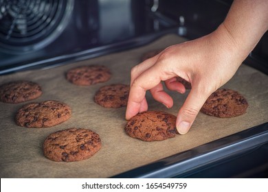 Person Taking Baked Homemade Chocolate Chip Cookie From Baking Tray. Close Up.