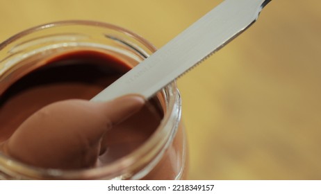 Person Taking Dollop Of Chocolate Nut Butter With Table Knife To Smear It On Bread Toast. Hazelnut Cream.