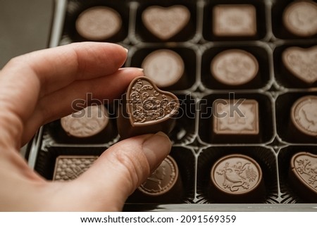 Person taking heart-shaped chocolate sweet from candy box