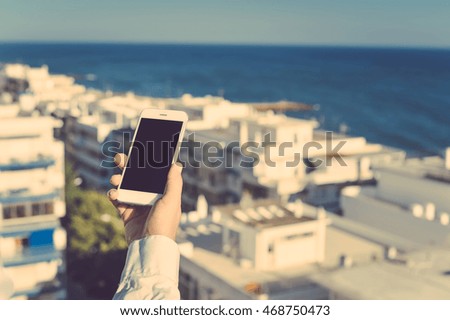 Person taking photo of city panorama on mobile smartphone, sunny day outdoors background