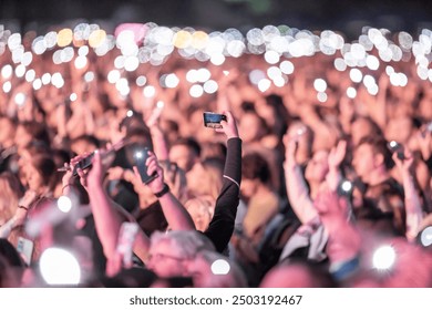 Person taking a photo with smartphone at concert - Powered by Shutterstock