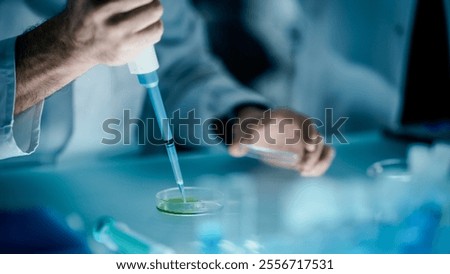Person Taking a Sample with a Micro Pipette and Dropping the Blue Liquid into a Petri Dish. Close Up of Anonymous Scientists Conducting Medical Research and Discovery in Science Lab